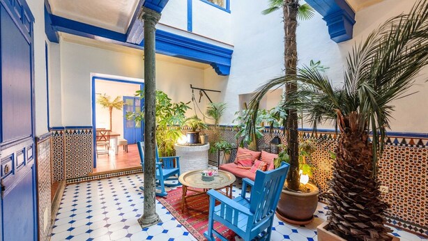 Un cortile accogliente con pavimento piastrellato, mobili blu e piante in vaso.