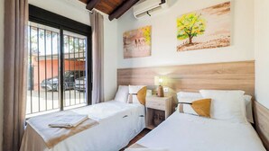 A hotel room with two beds, a nightstand, a lamp, and artwork on the wall. - Encina de Alhaurín Alhaurín el Grande by Ruralidays (Málaga)
