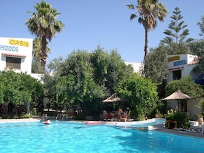 Relax by the serene pool surrounded by lush greenery and palm trees.
