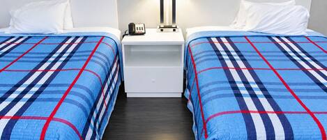 Una habitación de hotel con dos camas, una mesita de noche con lámpara y teléfono.
