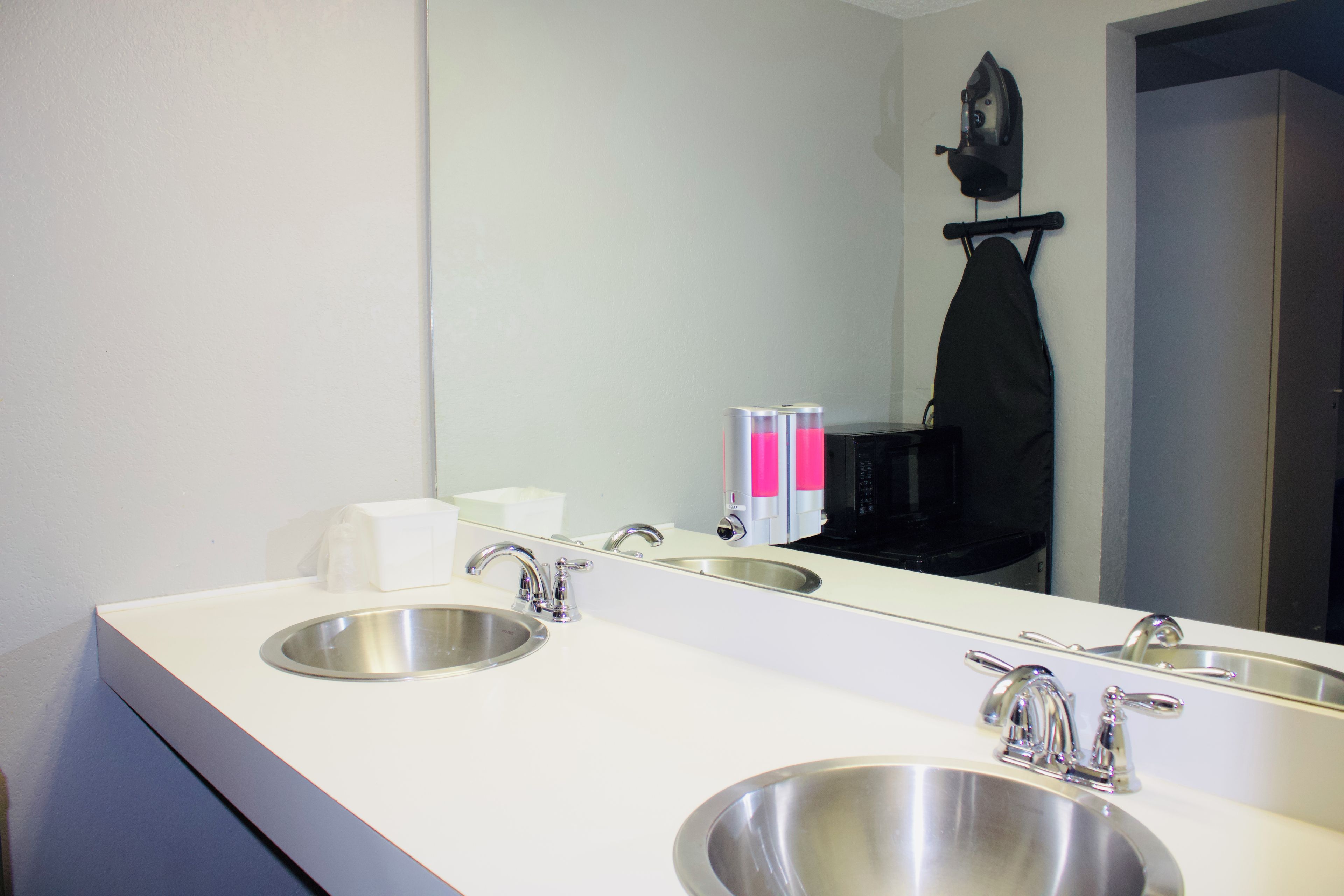 A hotel bathroom with two sinks, a mirror, and a towel rack.