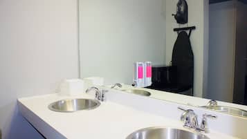 A hotel bathroom with two sinks, a mirror, and a towel rack.