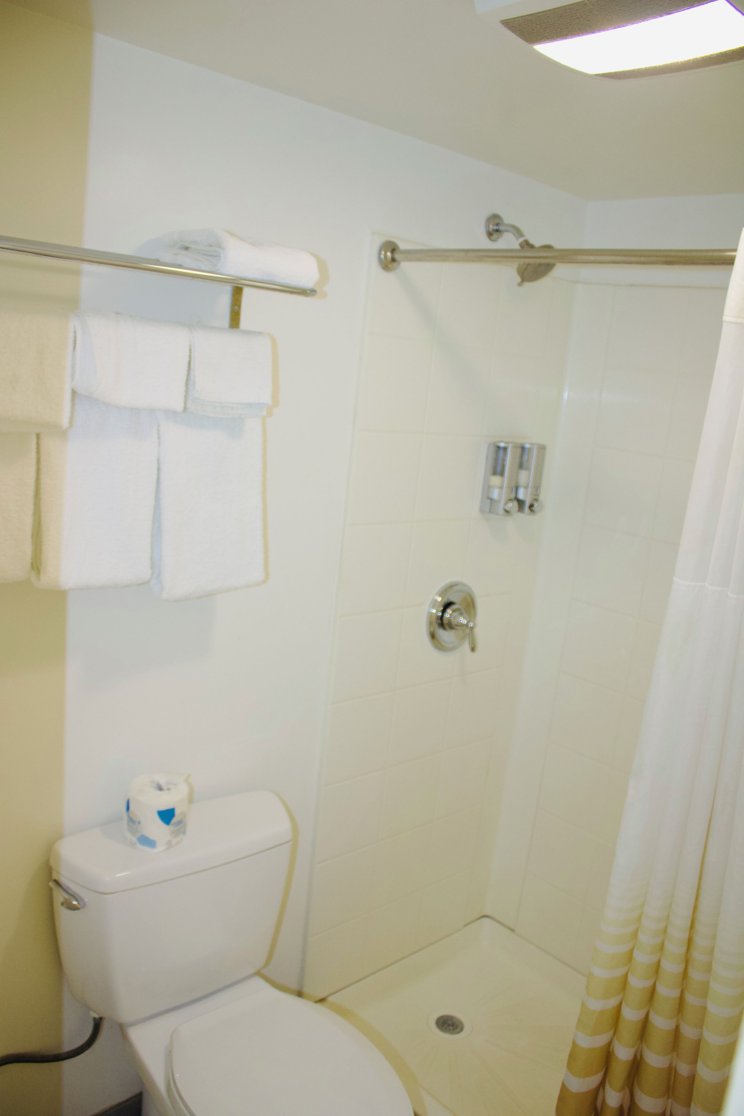 A bathroom with a toilet, a shower with a glass door, and a towel rack with towels.