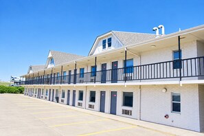 Un motel con varias habitaciones, un estacionamiento y un cielo azul despejado.