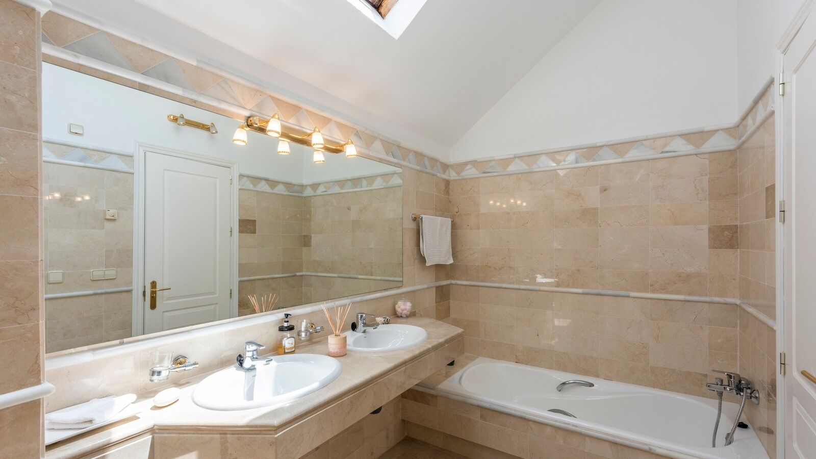 A bathroom with two sinks, a bathtub, and a large mirror.