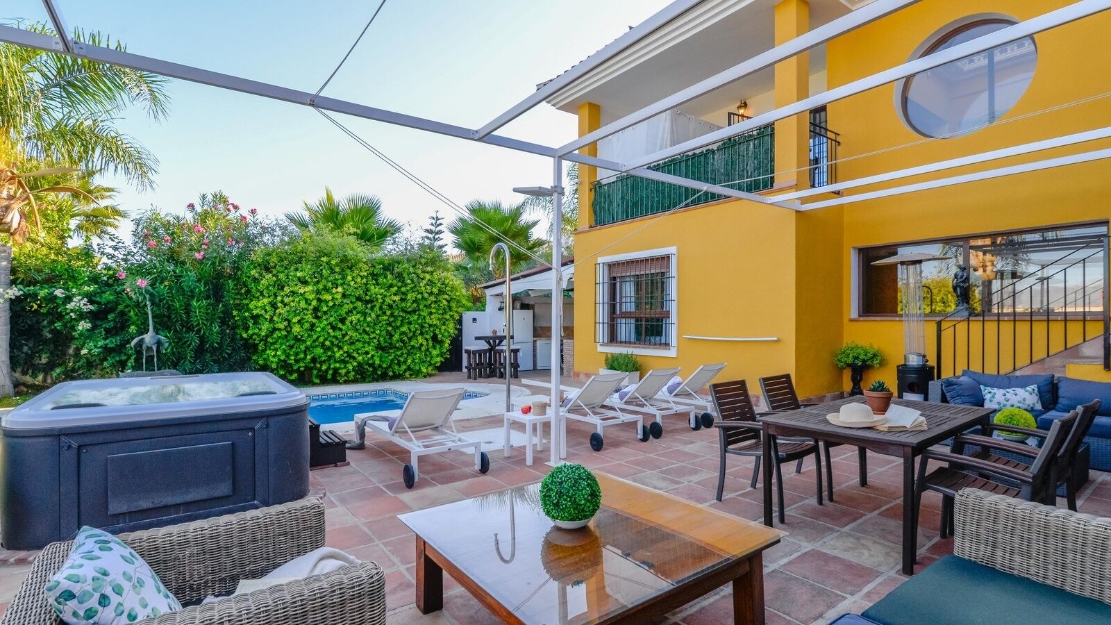 A patio area with a hot tub, lounge chairs, a dining table, and a sofa.