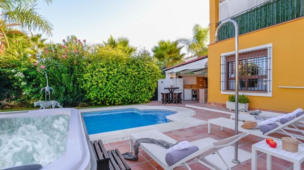 A swimming pool with lounge chairs and a hot tub, surrounded by greenery and a patio area. - Villa Estrella Coín by Ruralidays (Málaga)