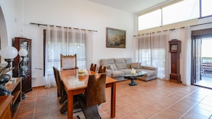 A spacious living room with a dining area, a sofa, and a large window providing natural light. - Villa Estrella Coín by Ruralidays (Málaga)