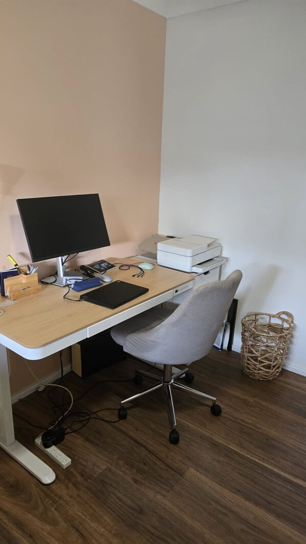 A home office setup with a desk, computer, printer, and office chair.