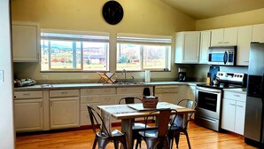 A spacious kitchen with a dining area, wooden flooring, and large windows offering a view of the outdoors. - IceBerg Farms, even a Yeti can chill here!!!! (Silt)
