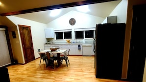 A spacious kitchen with wooden flooring, a dining area with a table and chairs, and a refrigerator. - IceBerg Farms, even a Yeti can chill here!!!! (Silt)