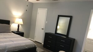 A bedroom with a bed, a dresser, a mirror, a nightstand, and a chair. - Furnished 1Bed 1Bath (Van)