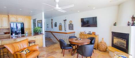 Amplia sala de estar con cocina, mesa de comedor, sofá de cuero y chimenea.