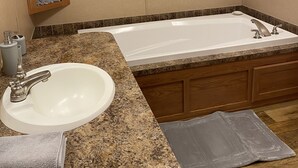 A bathroom with a freestanding bathtub, a sink, and a wooden medicine cabinet.