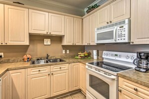 A kitchen with light wooden cabinets, a stainless steel sink, a microwave, a stove, and a coffee maker. - 3 Mi to Beach & Golf: Resort Condo in Myrtle Beach (Myrtle Beach)