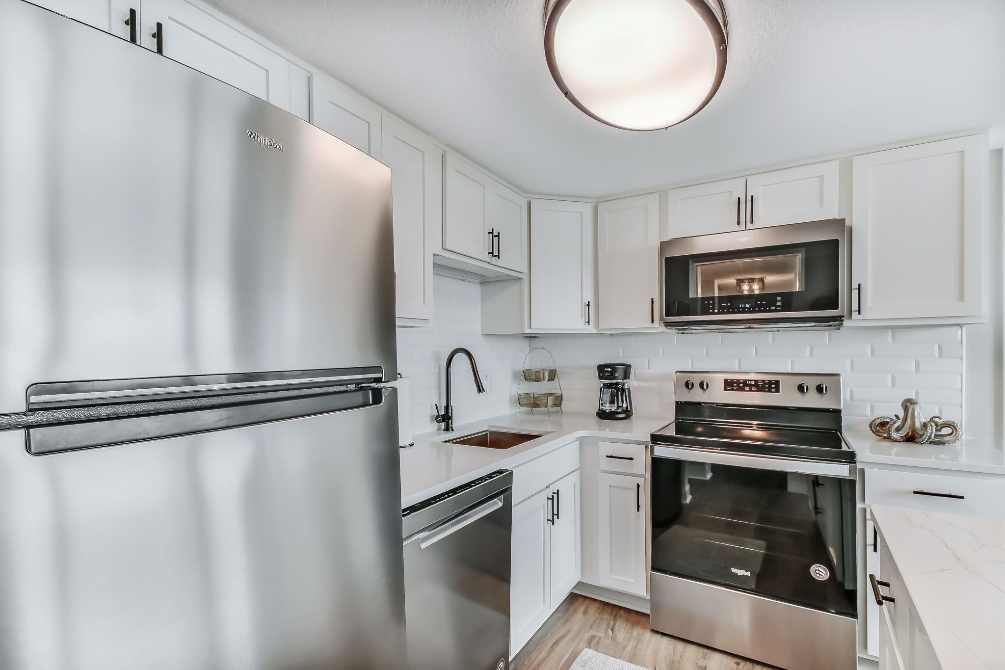 A modern kitchen with stainless steel appliances, white cabinetry, and a built-in oven.
