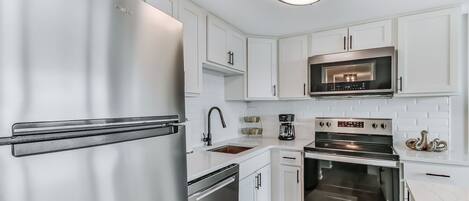 A modern kitchen with stainless steel appliances, white cabinetry, and a built-in oven.