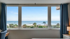 A hotel room with a large window offering a view of the beach and ocean. - Beautiful Beachfront Condo - Access to Amelia Island Golf & Beach Club (Fernandina Beach)