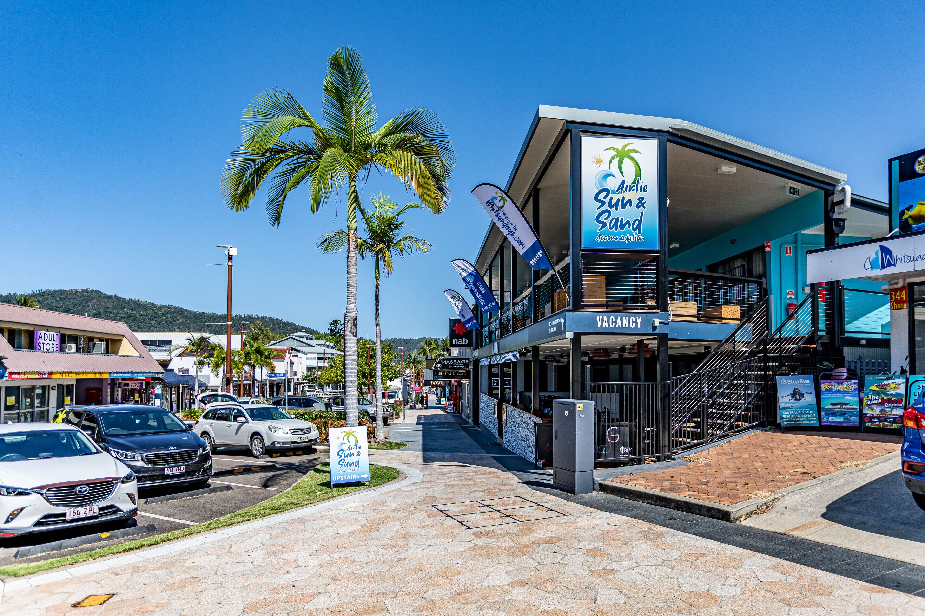 A commercial building with a sign for 'Sun & Sand' and 'VACCANCY' services.