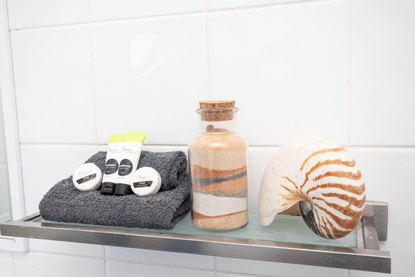 Un estante en el baño con una toalla, una botella de champú y una concha marina.