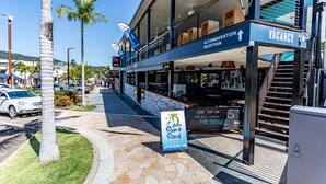 A hotel with a reception area, a sign for 'Acacia Sun & Sand', and a staircase leading to the upper floor. - Airlie Sun & Sand Accommodation Studio 1 (Airlie Beach)