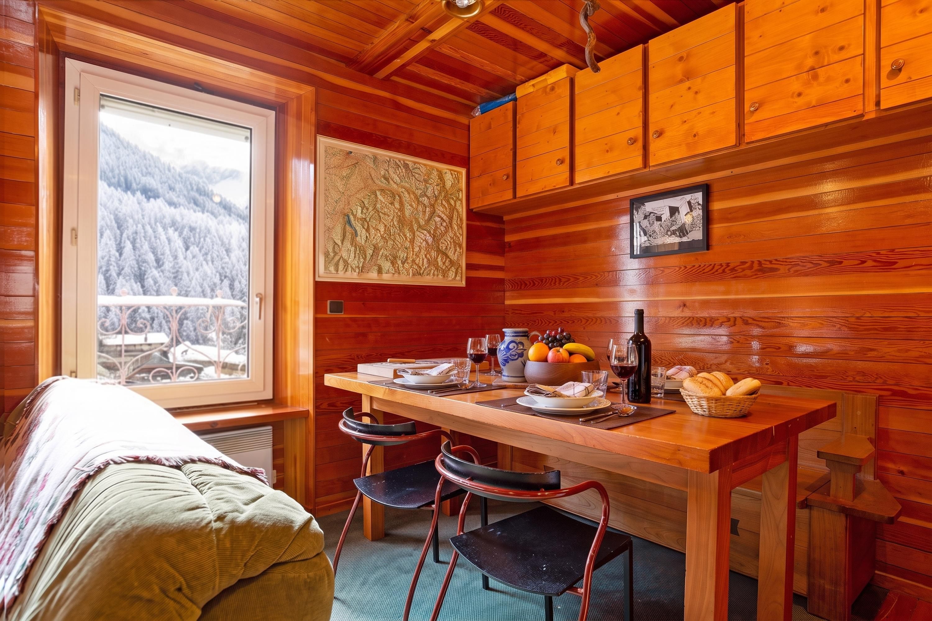 L’intérieur d’un chalet accueillant, avec un décor en bois, une table à manger mise avec des assiettes, des verres et une bouteille, et un lit recouvert d’une couverture.
