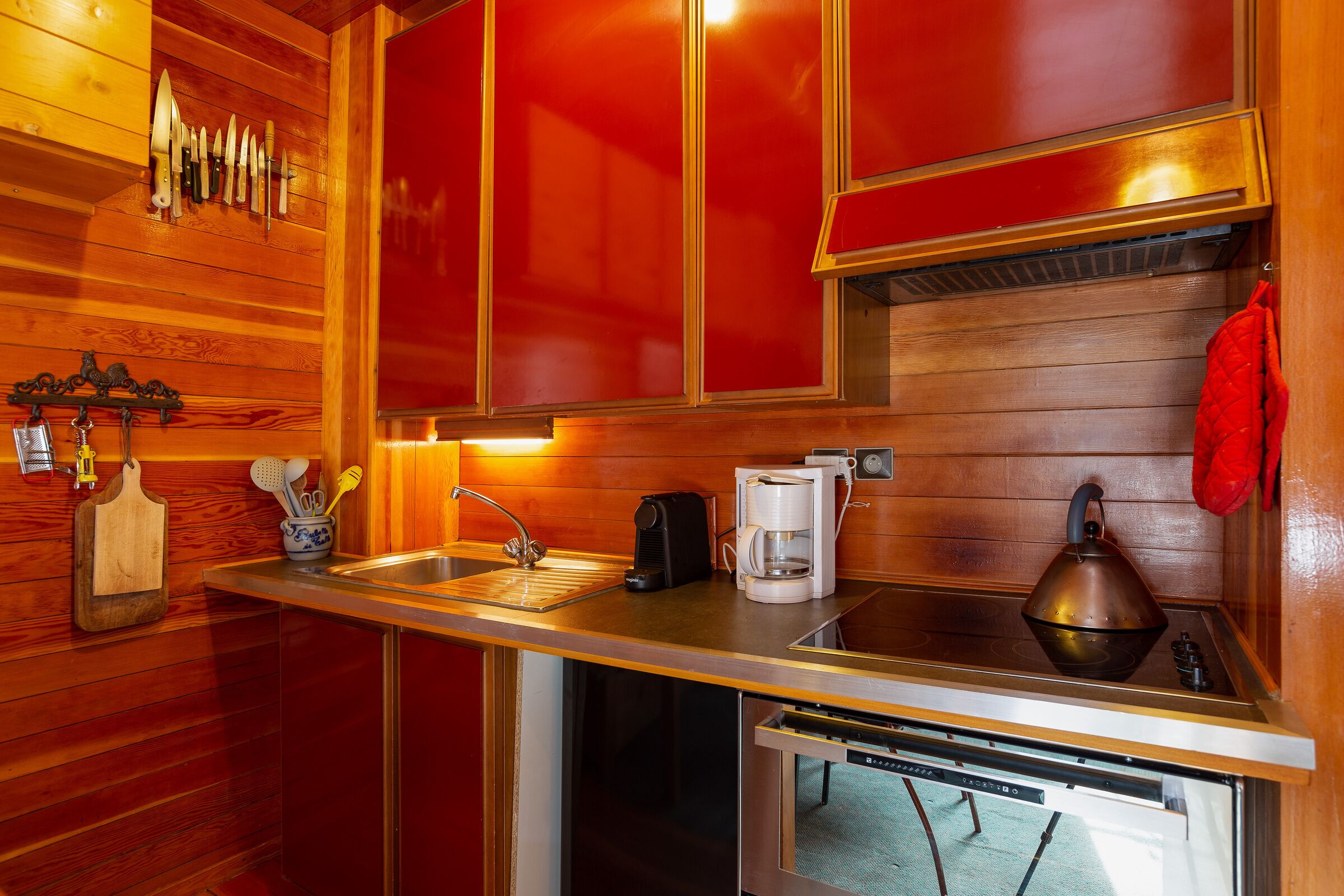 Een keuken met houten wanden, een roestvrijstalen aanrecht, een koffiezetapparaat, een waterkoker en een spoelbak.