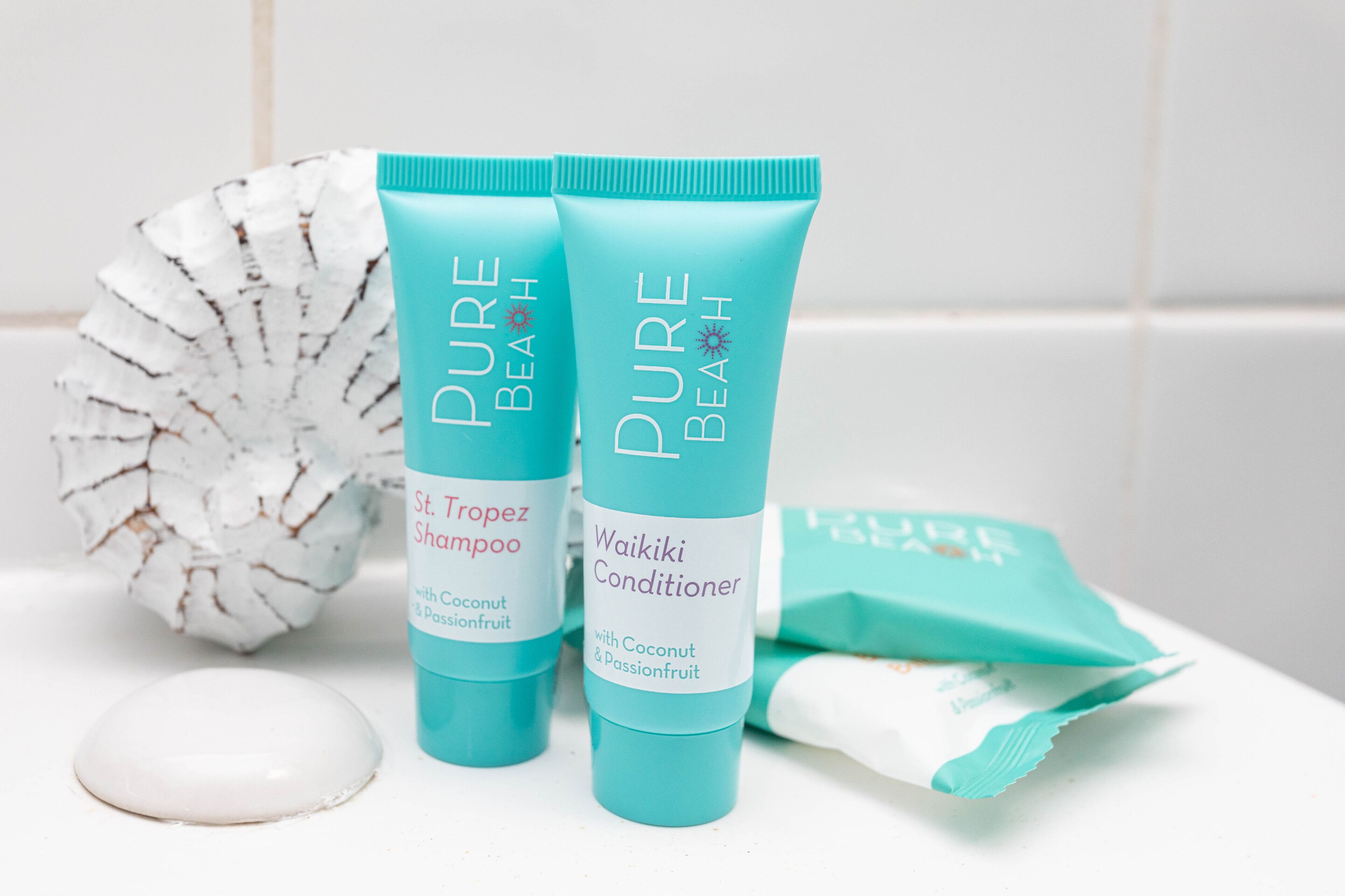 Two bottles of Pure Beach shampoo and conditioner, a white soap, and a white decorative object.