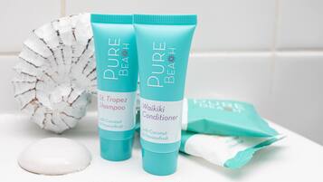 Two bottles of Pure Beach shampoo and conditioner, a white soap, and a white decorative object.