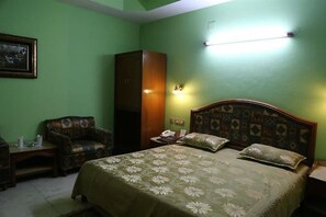 Um quarto com uma cama, uma cadeira, uma mesa de cabeceira e um guarda-roupa.