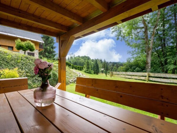 Un banco de madera con vistas despejadas a un jardín exuberante y una cerca de madera.