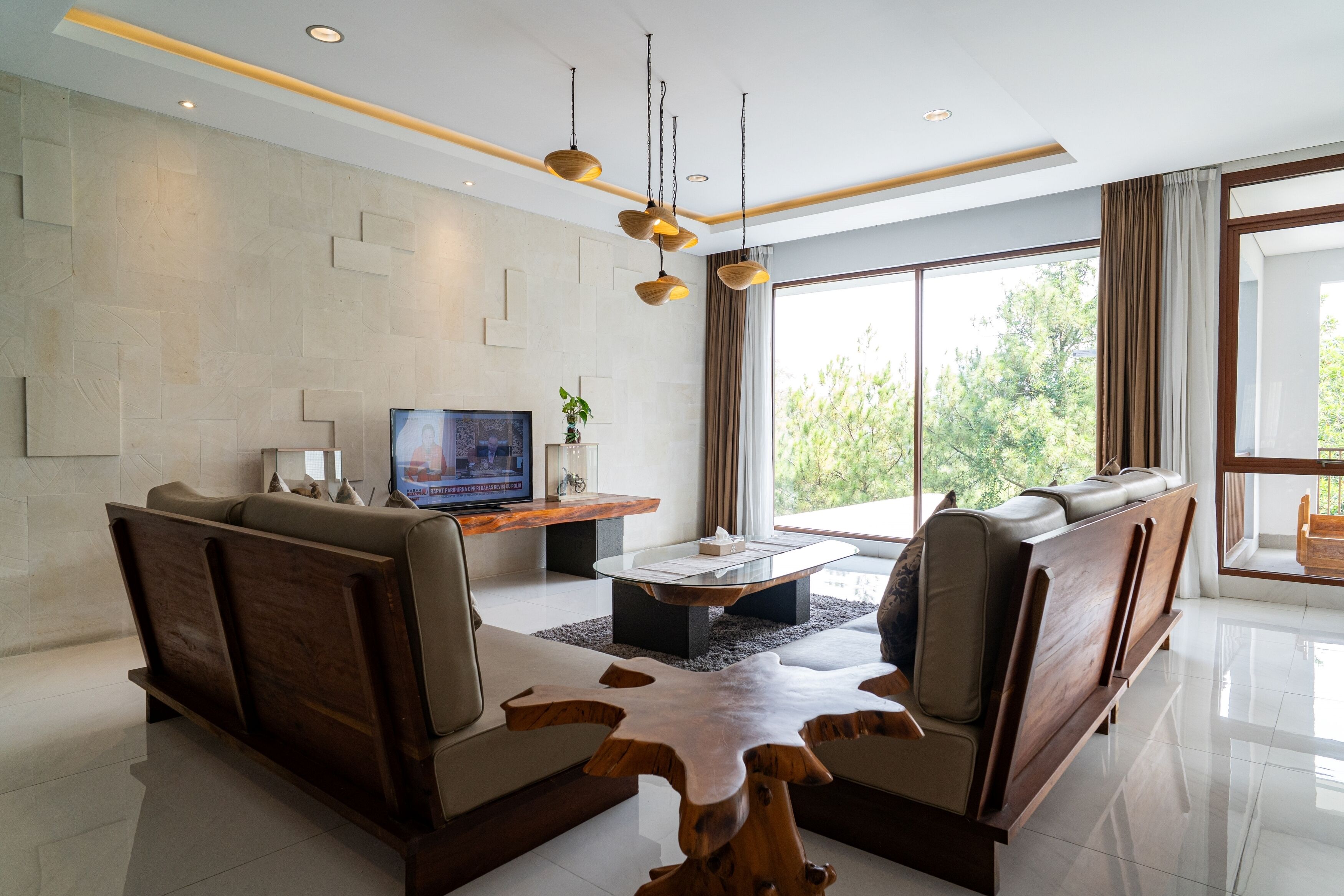A modern living room with a sofa, coffee table, TV, and large windows.