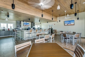 A spacious indoor area with a bar, seating arrangements, and a television mounted on the wall.