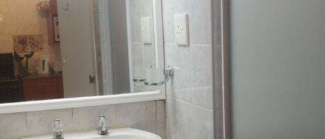 A bathroom with a white sink, a mirror, and a towel rack.