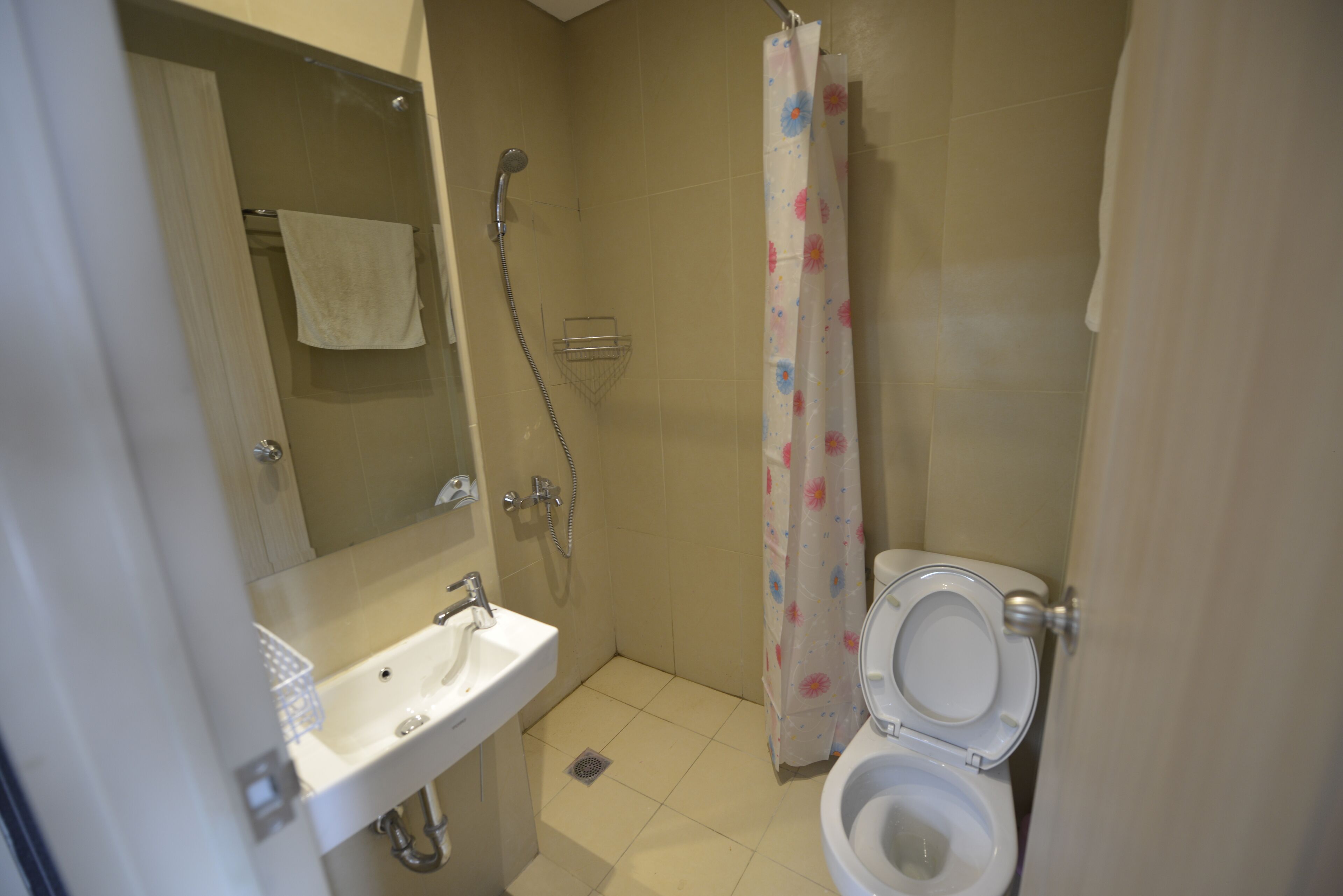 A small bathroom with a sink, toilet, shower, and a towel hanging on the wall.