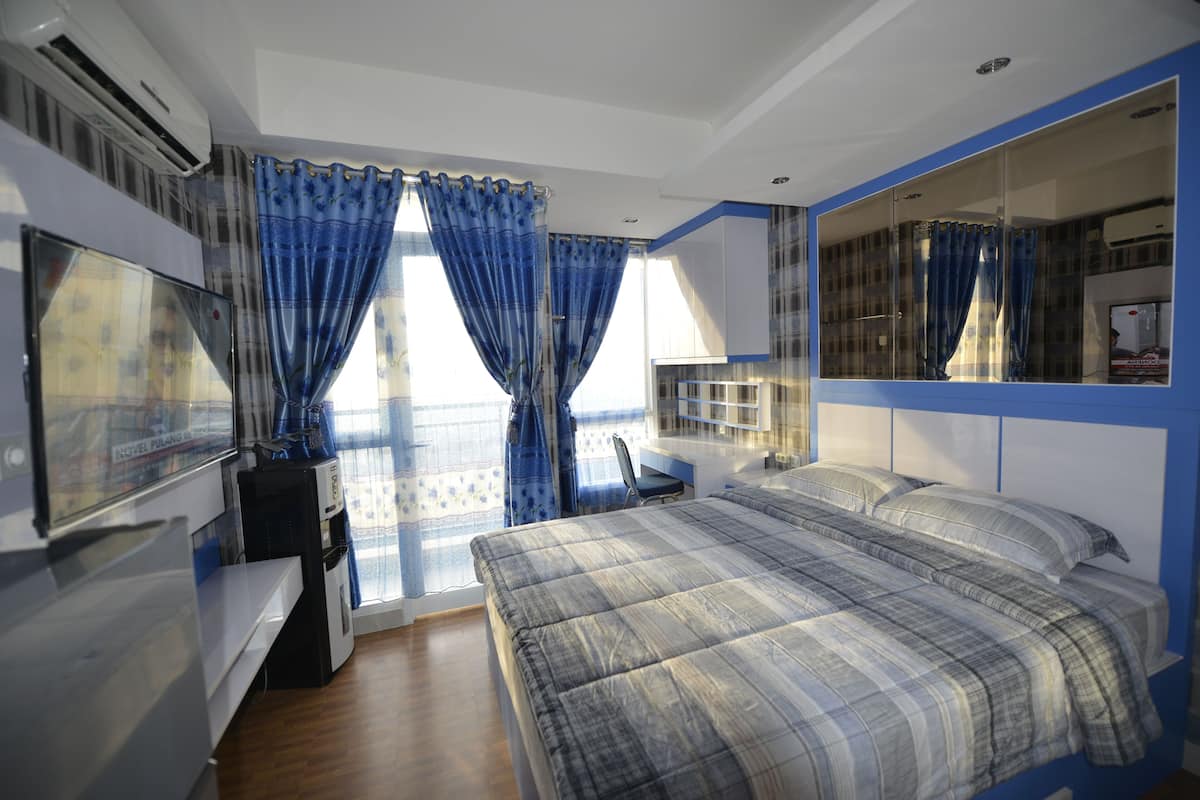 Une chambre d’hôtel avec un lit, un bureau et un grand miroir.
