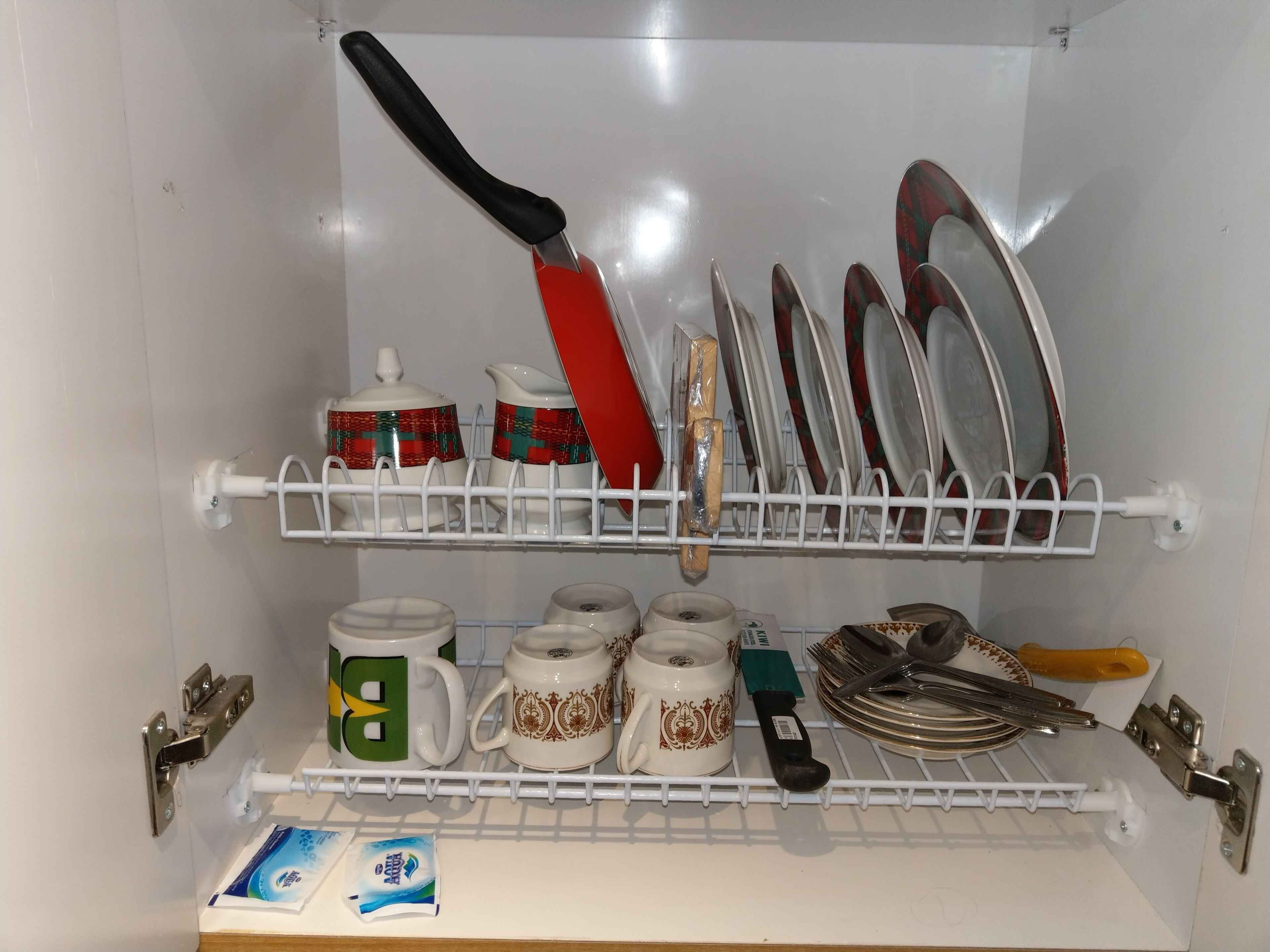 A kitchen with white cabinets, a white countertop, and a white hanging rack for dishes.
