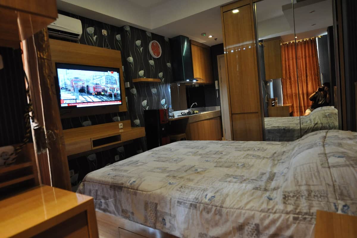 Une chambre d’hôtel avec un grand lit, une télévision, un petit coin cuisine et un miroir.