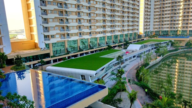 A high-rise hotel with multiple balconies, a rooftop pool, and a landscaped terrace. - Quiet 3BRs pool and lake view (Cikarang)