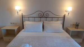 A neatly made bed with white linens and two bedside tables, each with a lamp. - Royal Rose (Corfu)