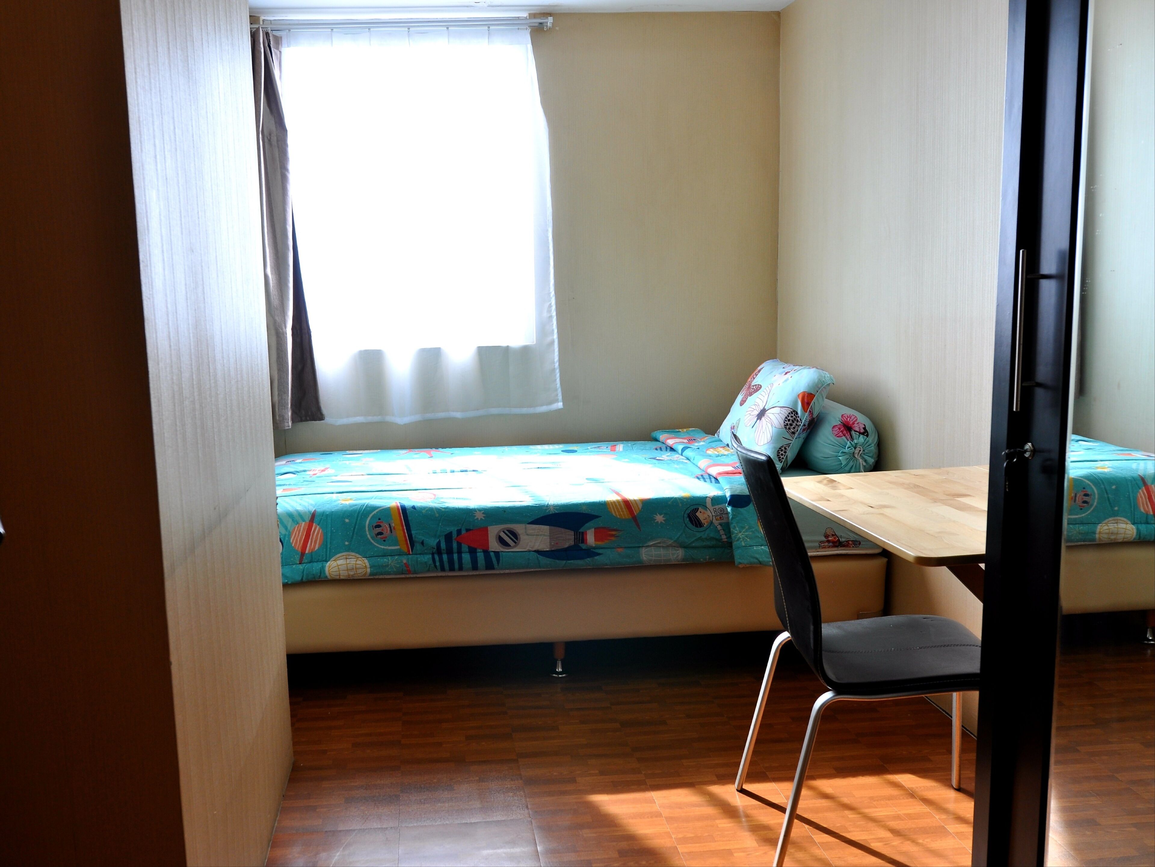 Une petite pièce avec un lit, une table et une chaise.