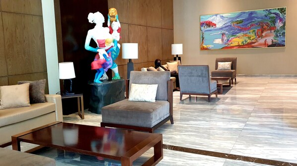 A lobby with seating arrangements, a statue, and a painting on the wall. - Spacious room at 23th city view (Jakarta)