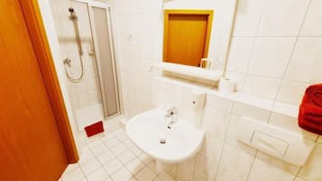 Un baño con ducha, lavabo, espejo e inodoro.