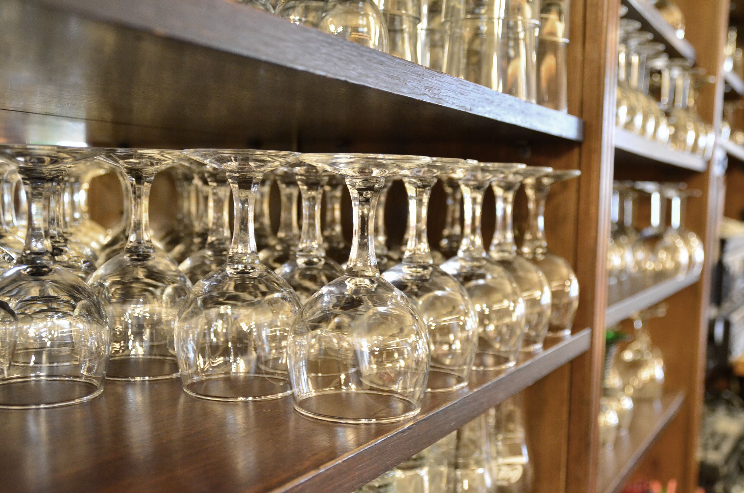 A shelf with multiple wine glasses.