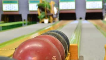 Bolera con múltiples pistas y pelotas de bolos alineadas al inicio.