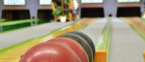 A bowling alley with multiple lanes and bowling balls lined up at the start.