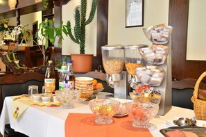 A breakfast buffet setup with various food items, condiments, and a coffee machine. - Hotel Deutsches Haus (Dingelstaedt)