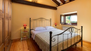 A bedroom with a bed, wooden floor, a window, and a radiator.