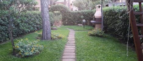 A garden pathway leading to a building with a stone wall and a lamp post.