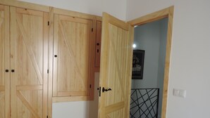 A room with wooden wardrobes, a bed with a white bedspread, and a door leading to another room.